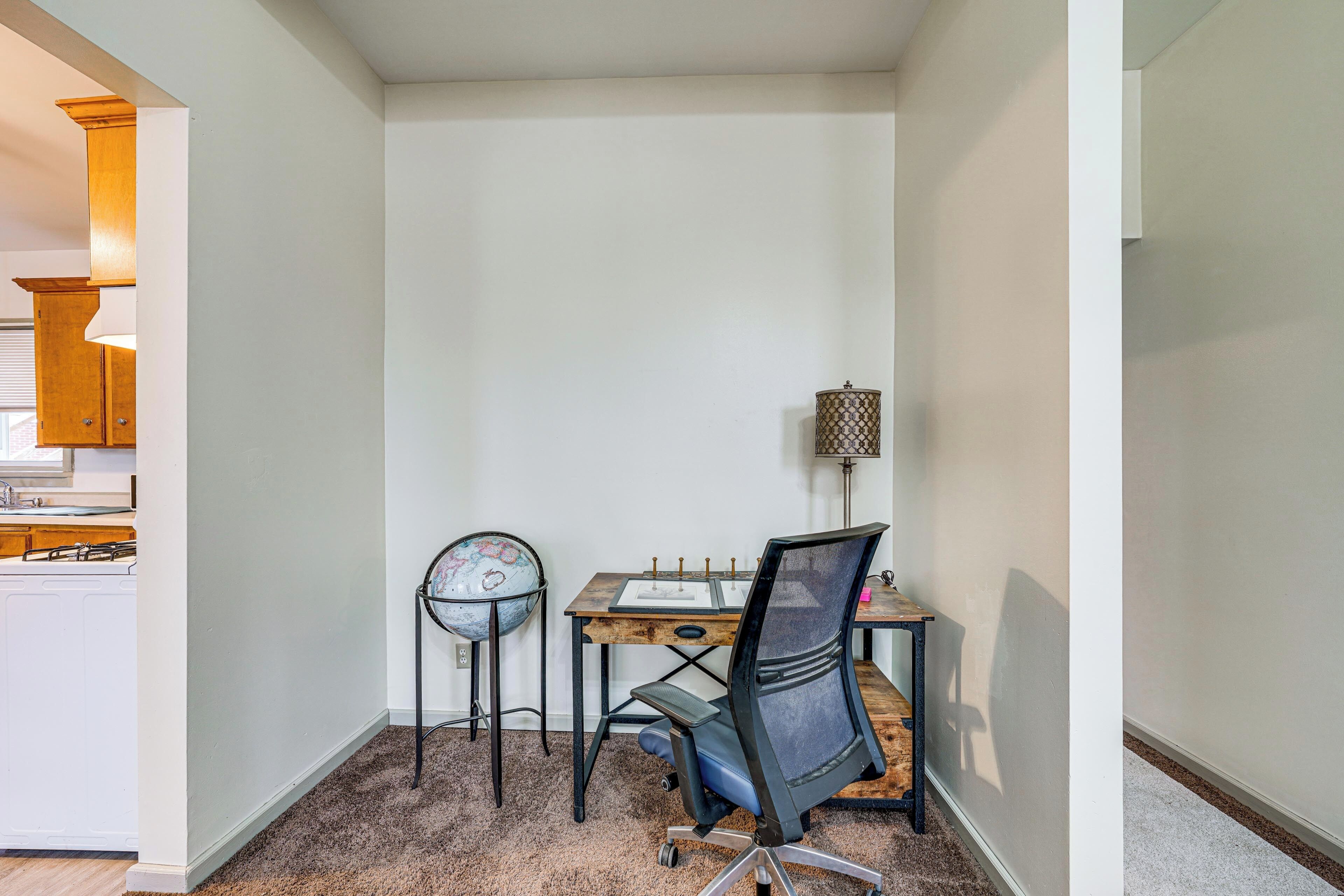 A small office space with a desk, chair, lamp, and globe.