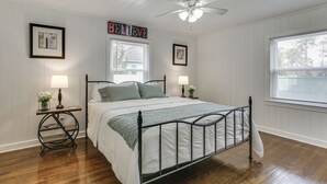 Ein Schlafzimmer mit einem Bett, zwei Nachttischen, einem Deckenventilator und einem Fenster mit Jalousien.