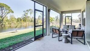 A spacious balcony with a view of a lake and trees, furnished with a sofa and chairs. - 1 Mi to Boat Launch: Canal-View Cape Coral Gem (Cape Coral)