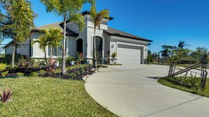 A residential house with a driveway, palm trees, and a well-maintained lawn. - 1 Mi to Boat Launch: Canal-View Cape Coral Gem (Cape Coral)