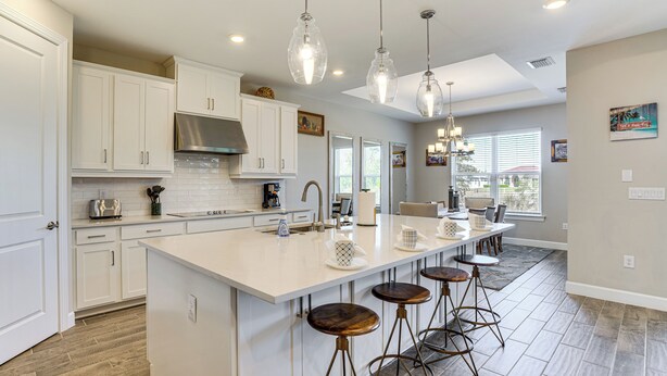 A modern kitchen with white cabinetry, a large island with stools, pendant lighting, and a view to the dining area. - 1 Mi to Boat Launch: Canal-View Cape Coral Gem (Cape Coral)