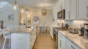 Uma cozinha moderna com bancadas de granito, eletrodomésticos de aço inoxidável e iluminação pendente.