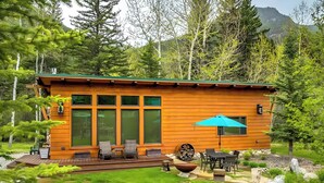 A wooden cabin with large windows, outdoor seating, and a fire pit. - Boulder Dreams Guest House w/ Fire Pit! (Mc Leod)