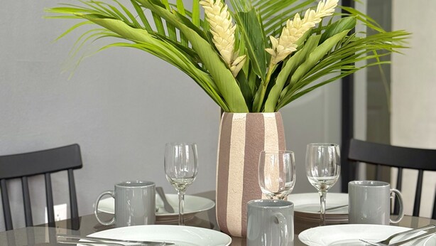 A dining table with a vase of flowers, plates, and glasses. - Apartamento Lapas  (La Fortuna)