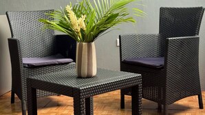 Two wicker chairs with cushions, a small table with a plant, and a wooden parquet floor. - Apartamento Lapas  (La Fortuna)