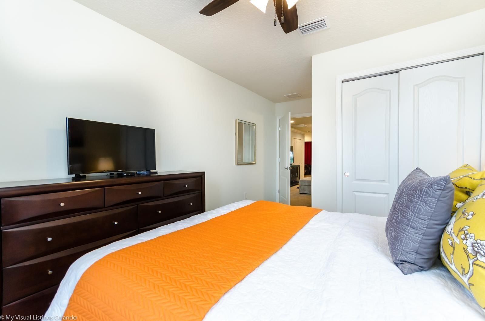 A bedroom with a bed, a TV on a dresser, and a closet.