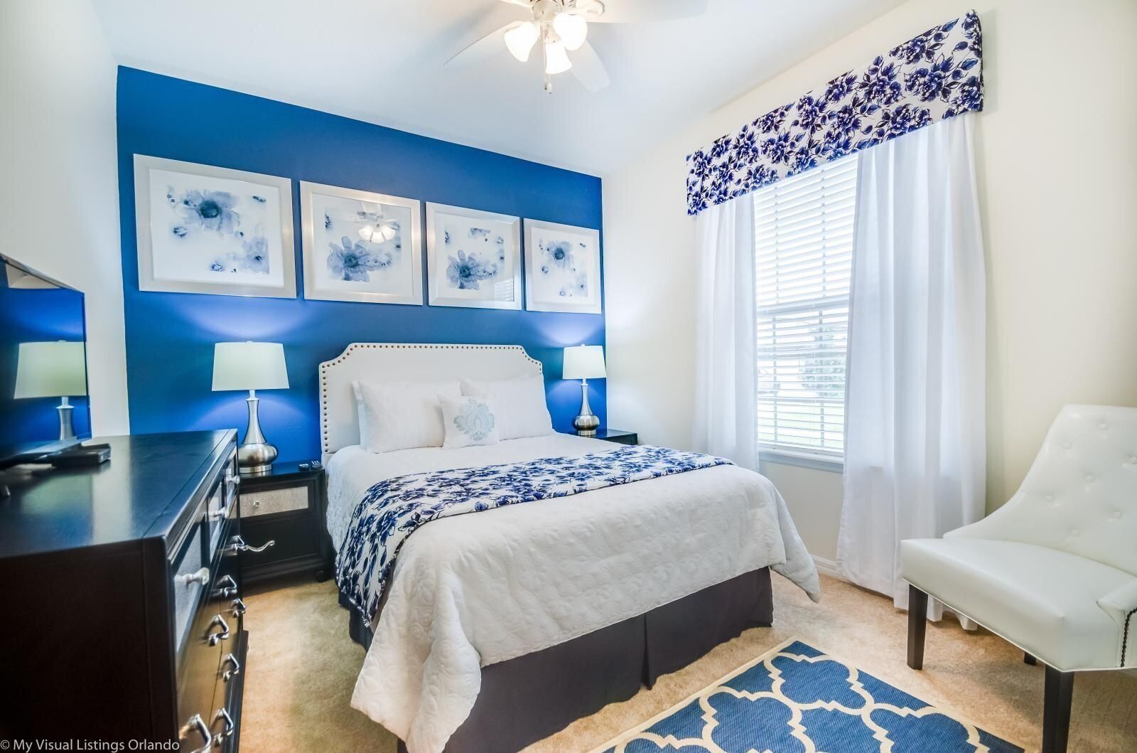 A bedroom with a bed, bedside tables, a desk, a chair, and a window with curtains.