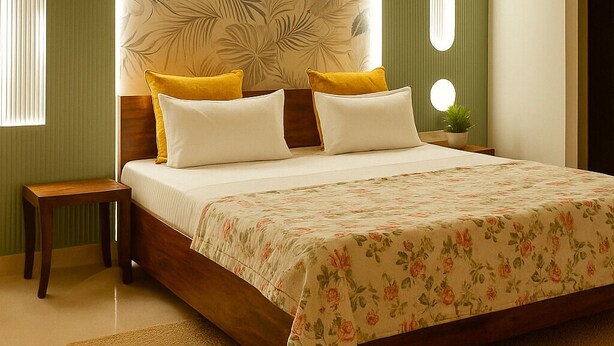 A bedroom with a large bed, green walls, and a floral bedspread. - 2-bedroom apartment in awesome New Delhi with AC for comfort (New Delhi)