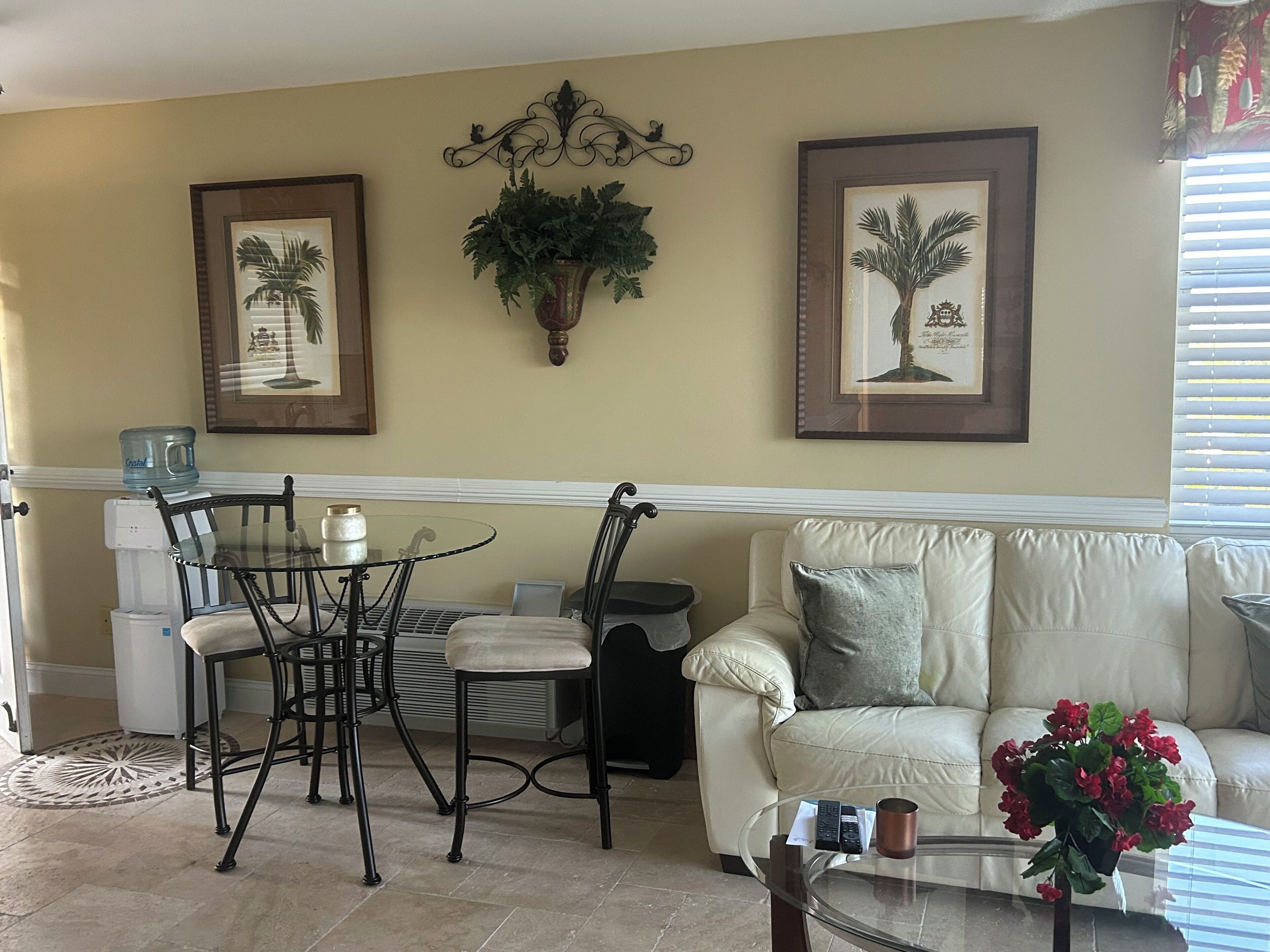 Un salon comprenant un coin repas, un canapé, une table basse et deux tableaux encadrés accrochés au mur.