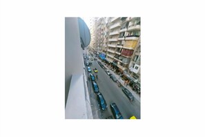 A street view with parked cars and a building with balconies. - Serene 2-bedroom apartment in the heart of Alexandria Governorate (Alexandria Governorate)