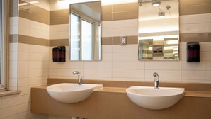 Un baño con dos lavamanos, un espejo y una ventana.