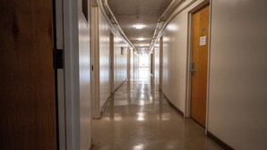 Un pasillo largo y estrecho con puertas a ambos lados, que conduce a habitaciones.
