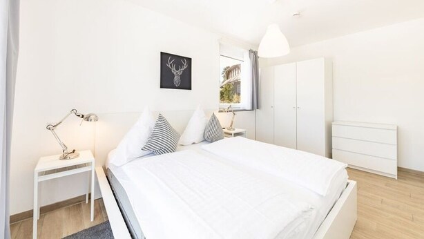 Un dormitorio moderno con cama, mesitas de noche, armario y un cuadro en la pared.