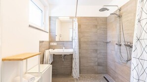 Un baño moderno con ducha, lavamanos y espejo.