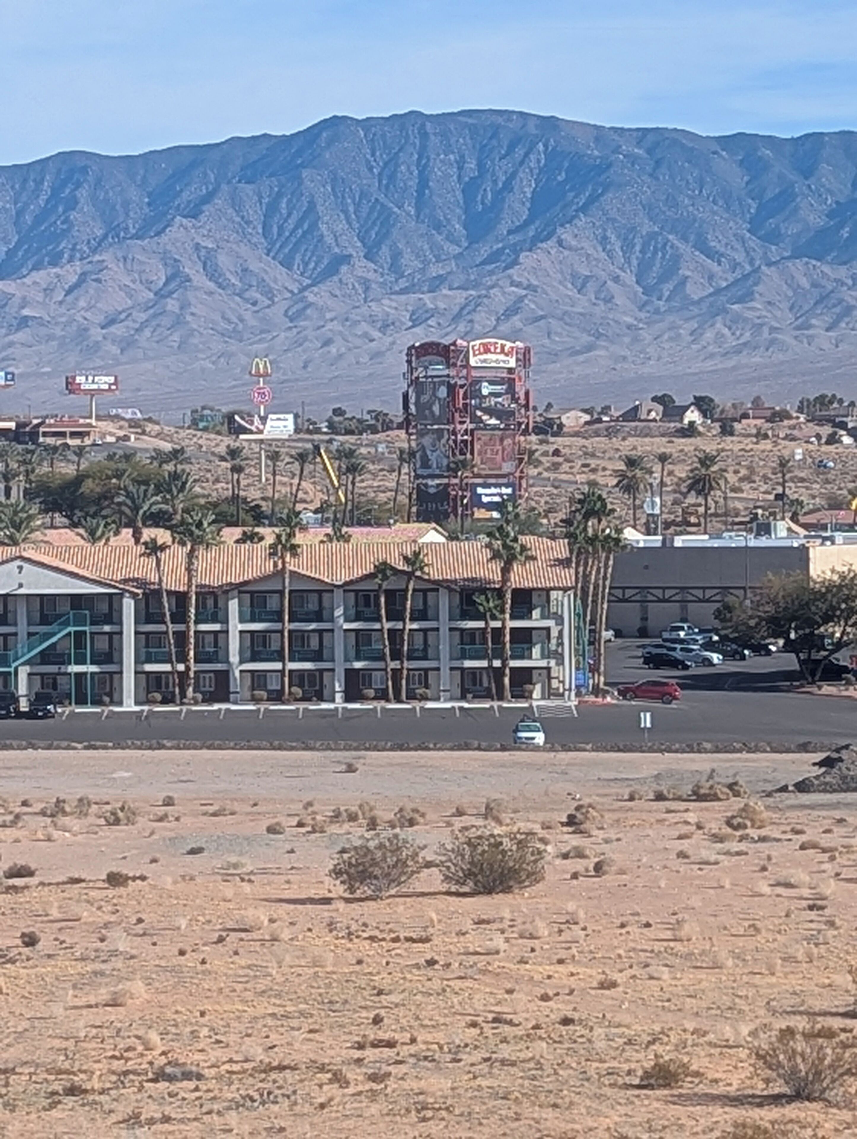 Un hôtel à plusieurs étages, doté d’un toit plat et bordé de palmiers.