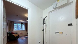 A hallway with a coat rack, a door with a handle, and a window with curtains. - Cosy 1BR Flat in East London (London)