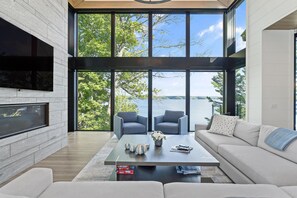 Een moderne woonkamer met een groot raam, een open haard en een bank.