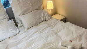 A neatly made bed with white linens and two towels folded in a cross shape, placed on the bed. - Modern & Cozy Apartment | Central Magdeburg | (Magdeburg)