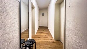A narrow hallway with wooden flooring, white walls, and a mirror on the left. - Modern & Cozy Apartment | Central Magdeburg | (Magdeburg)