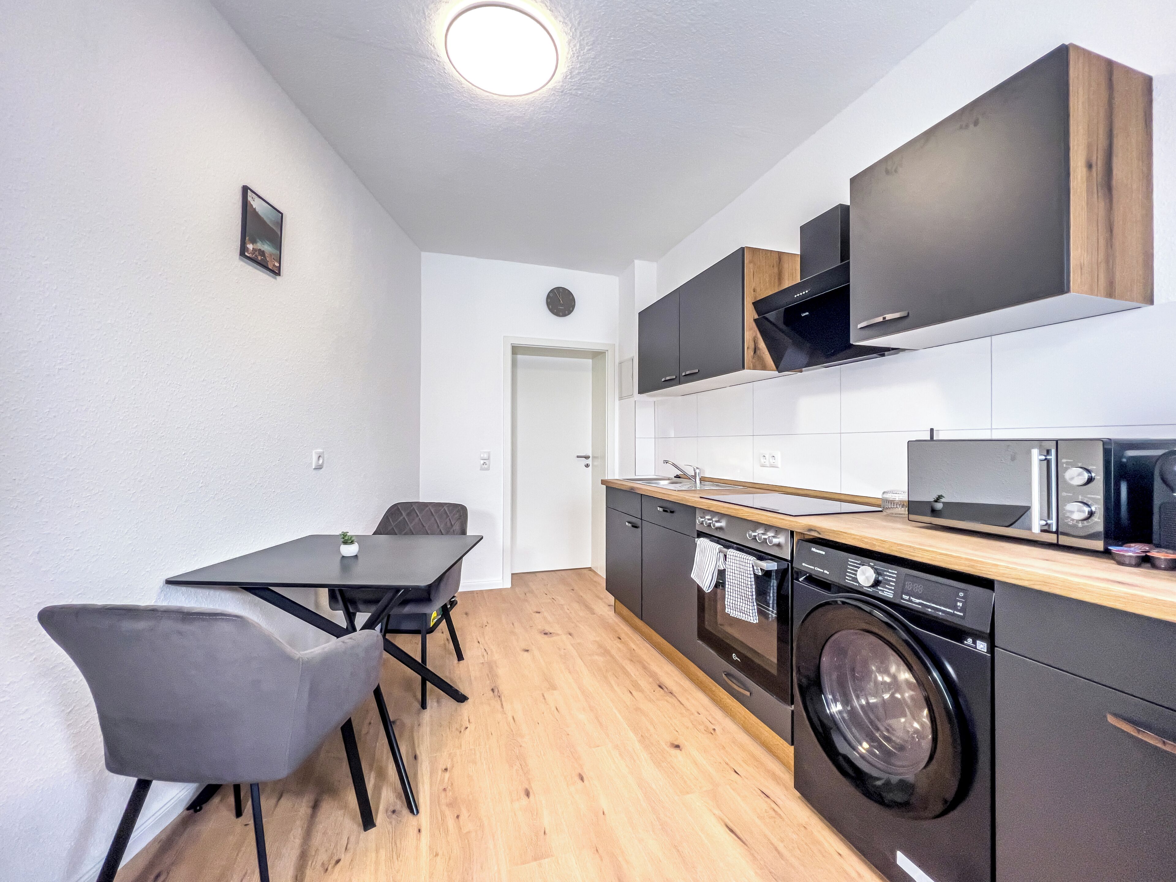 A compact kitchen with a washing machine, a microwave, and a sink.