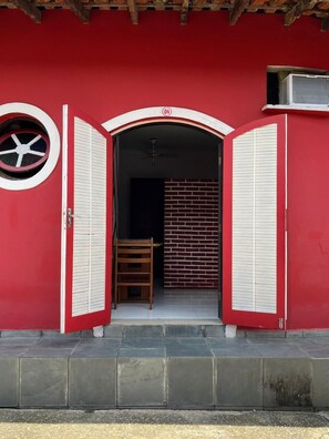 Um edifício vermelho com uma porta que dá para uma parede de tijolos e um ventilador de teto.