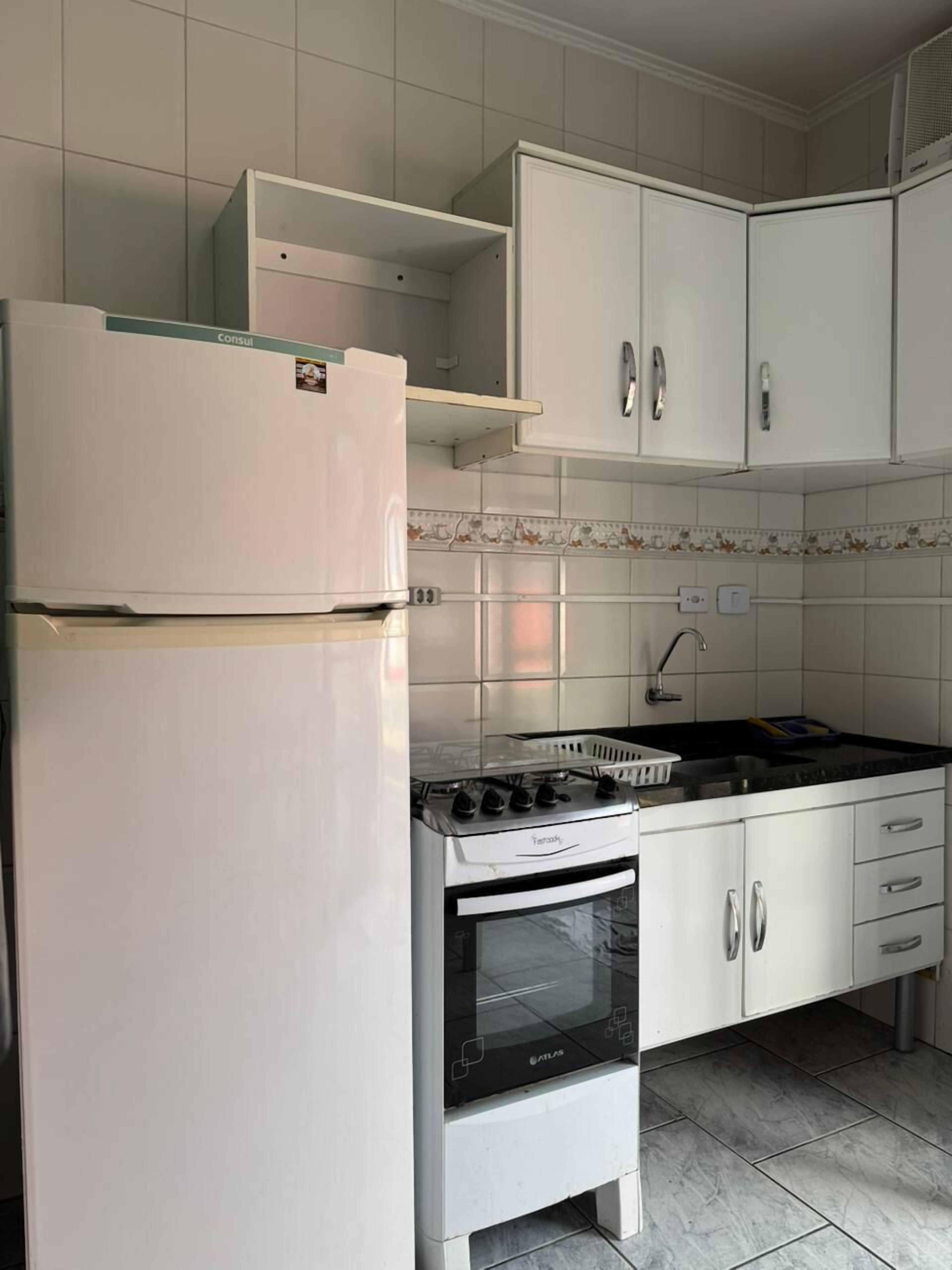 A kitchen with white cabinets, a refrigerator, a stove, and a sink.