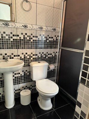 Une salle de bain équipée de toilettes, d’un lavabo et d’une poubelle.