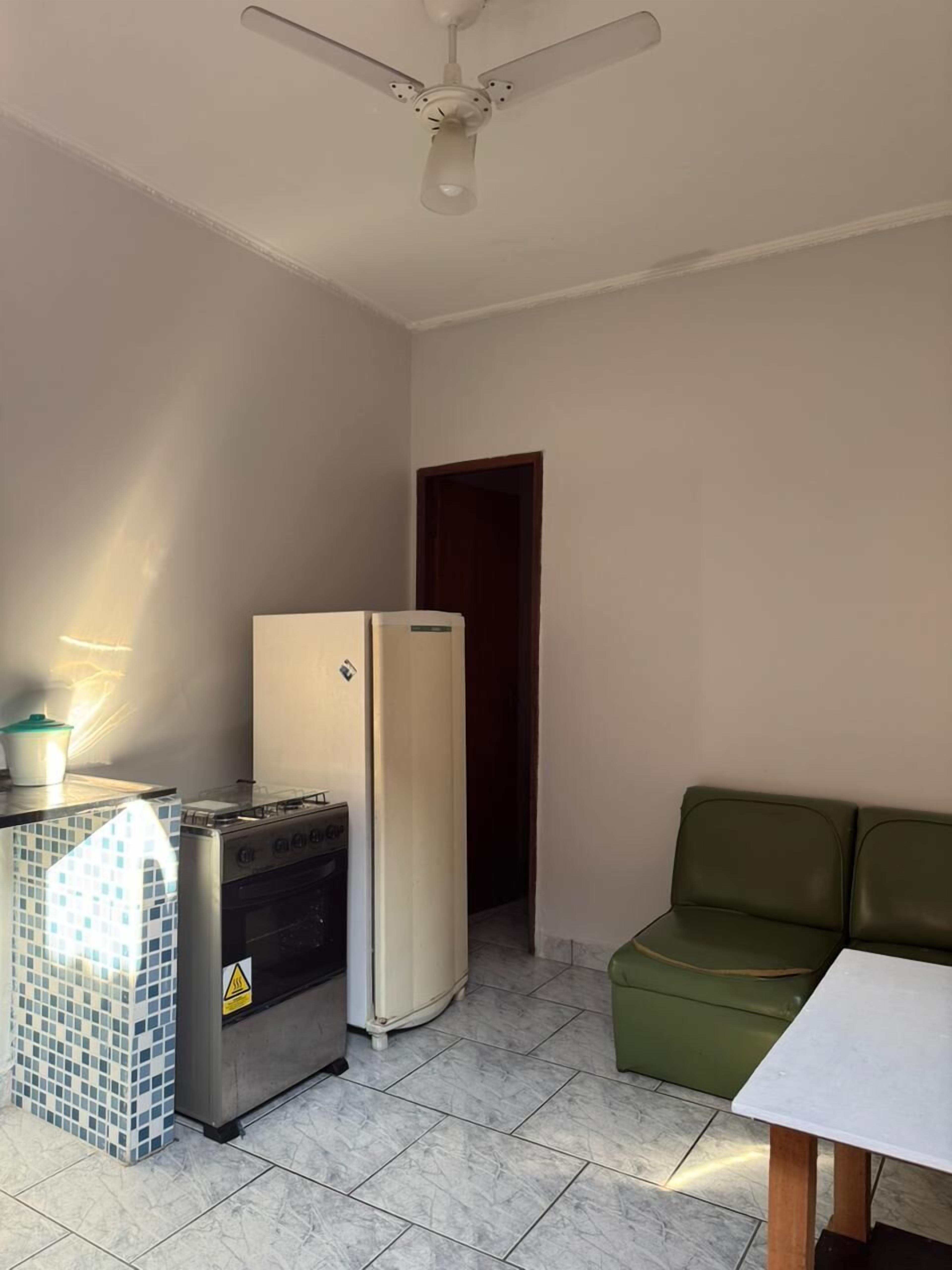 A compact kitchen with a refrigerator, stove, and tiled backsplash.