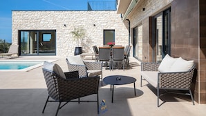 Une terrasse extérieure avec des murs en pierre, une piscine et des meubles modernes.