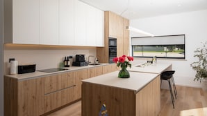 Une cuisine moderne avec des meubles en bois, un îlot central et une vue sur l’extérieur.