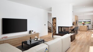 Un salon moderne avec un téléviseur à écran plat, une table basse noire et un canapé beige.