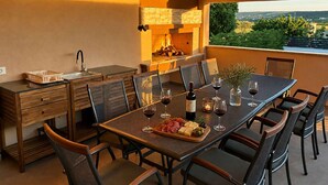 A dining area with a long table, chairs, a wine bottle, glasses, and a charcuterie board. - Stunning home in Gorica (Gorica)