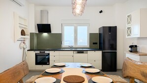A modern kitchen with white cabinets, a black refrigerator, and a dining table set for six. - Stunning home in Gorica (Gorica)