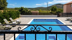 A rectangular swimming pool with a clear blue water, surrounded by lounge chairs and a metal railing. - Stunning home in Gorica (Gorica)