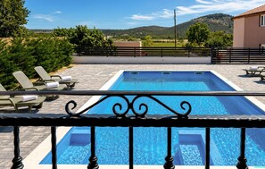 A rectangular swimming pool with a clear blue water, surrounded by lounge chairs and a metal railing. - Stunning home in Gorica (Gorica)