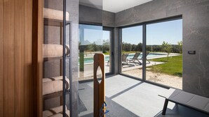 Un interior moderno con un amplio ventanal que da a un área de piscina al aire libre.