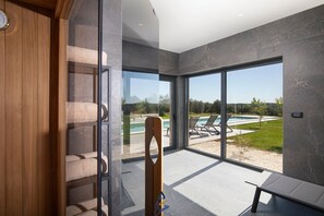 Interior moderno com uma grande porta de vidro que dá para uma área de piscina externa.