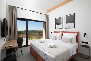 Ein Hotelzimmer mit Bett, Schreibtisch, Stuhl, Fernseher und Blick auf Pool und Landschaft.