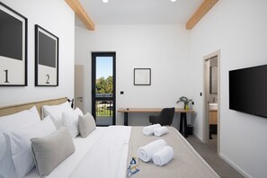 Una habitación de hotel moderna con cama, escritorio, silla, televisión y balcón con vistas.