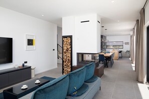 Una sala de estar moderna con televisor, sofá y comedor.