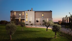 Una casa moderna de dos pisos con fachada de piedra, un césped cuidado y un cielo despejado.