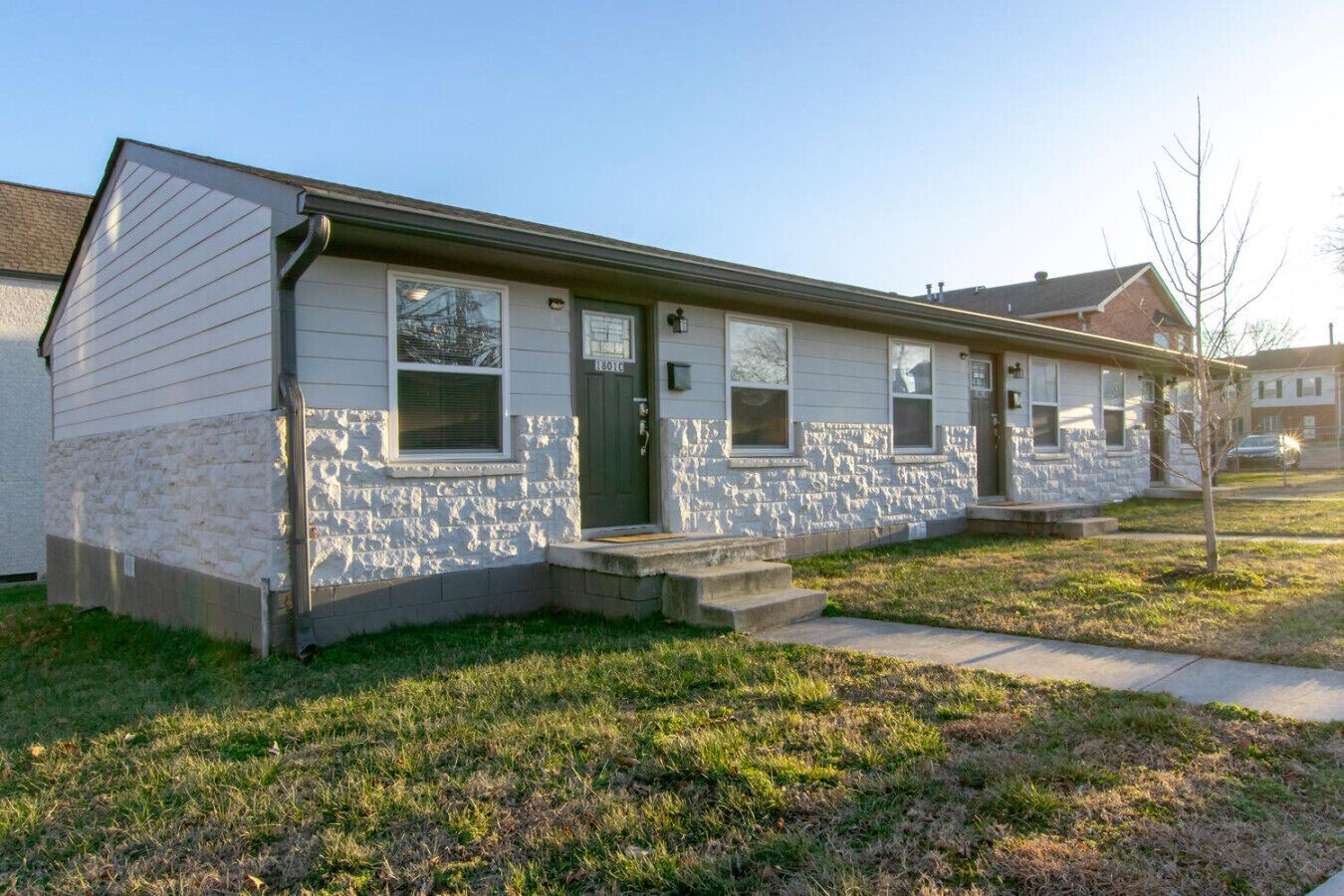 A single-story house with a stone facade, a front porch, and a small front yard.