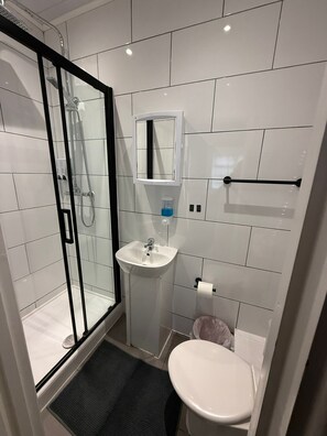 Un bagno moderno con cabina doccia in vetro, lavandino bianco, specchio e water.