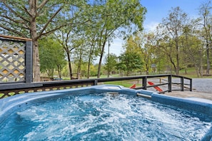Un bain à remous entouré d’arbres et doté d’une terrasse en bois.