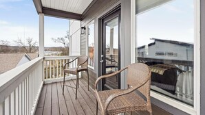 A covered porch with two wicker chairs, a glass door, and a view of neighboring houses. - 15 Min to Broadway - Fenced Yard - Family Friendly (Nashville)