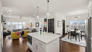 A modern kitchen with a central island, white cabinetry, and pendant lighting. - 15 Min to Broadway - Fenced Yard - Family Friendly (Nashville)