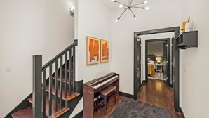 A staircase with a piano, a chandelier, and artwork on the walls. - 15 Min to Broadway - Fenced Yard - Family Friendly (Nashville)