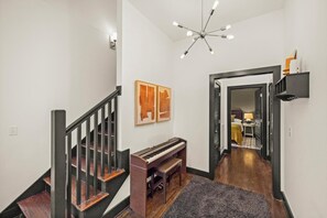 A staircase with a piano, a chandelier, and artwork on the walls. - 15 Min to Broadway - Fenced Yard - Family Friendly (Nashville)