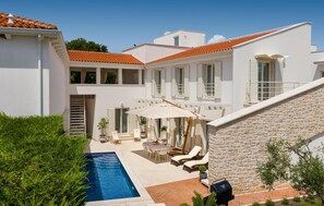 Une villa moderne dotée d’une piscine, d’un espace salon extérieur et d’un mur en pierre.