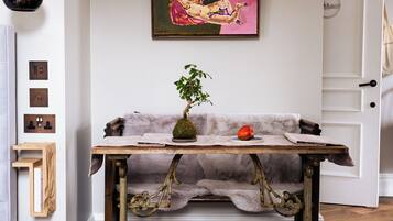 A room with a vintage wooden table, a potted plant, and a painting on the wall.